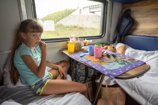 Ситуация в поезде, мама спит, дочь ест печенье — стоковое фото