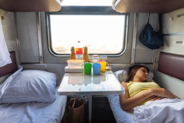 Ayrılmış bir koltuk tren vagonunun iç, bir kız alt rafta uyur