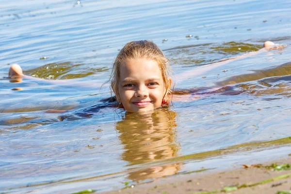Десятилетняя девочка лежит в воде у реки. — стоковое фото