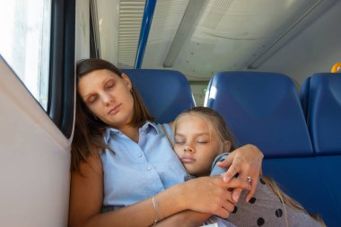 Anne ve kızı elektrikli bir trenin vagonunda uyuyorlar.