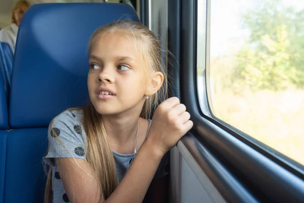 Tyttö istuu ikkunan vieressä sähköjunavaunussa. — kuvapankkivalokuva