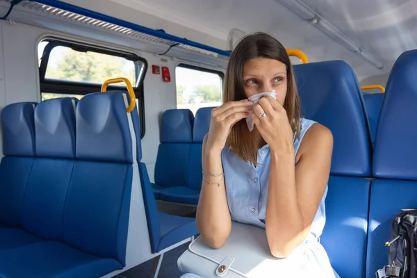 Una chica fría se sonó la nariz en una bufanda en un vagón de tren eléctrico — Foto de Stock