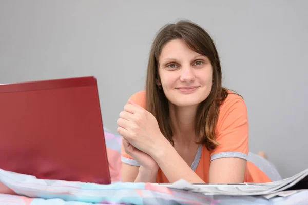 Das Mädchen Liegt Mit Laptop Und Zeitung Auf Dem Bett — Stockfoto