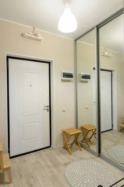 Hallway interior, large fitted wardrobe with large mirrors on the doors, entrance metal door