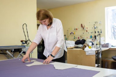 Kesici, maddenin kalıplarını atölyedeki büyük bir masanın üzerine serer.