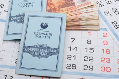 Anapa, Rusya - 29.06.2020: Takvimlerin arka planında beş binlik banknotlar ve tasarruf kitaplarından oluşan bir deste yer alıyor