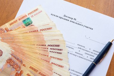 Arazi satışı sözleşmesinde bir vantilatör ve bir kalem içinde bir tomar para var.