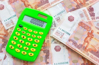 Paranın arka planında beş binlik banknotlar ve bir milyonluk hesap makinesi var.