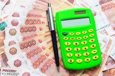 Yeşil bir hesap makinesi ve tükenmez kalem beş binlik banknotların üzerinde duruyor.