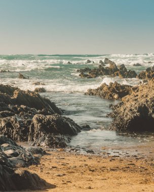 Dalgalar siyah kayalara çarpıyor