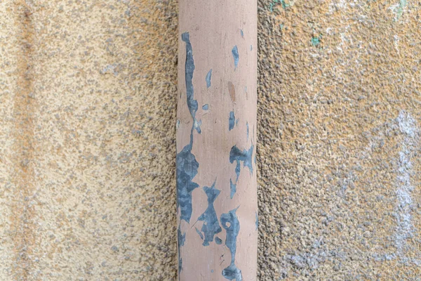 Vecchia parete colorata dipinta e lo stesso metallo colorato tubo dell'acqua esterno vernice intemperie dettaglio superficie screpolata — Foto Stock