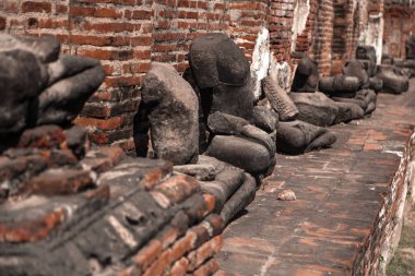 Ayutthaya Tayland 'daki tuğla duvarın yakınındaki taş heykellerin kalıntıları.