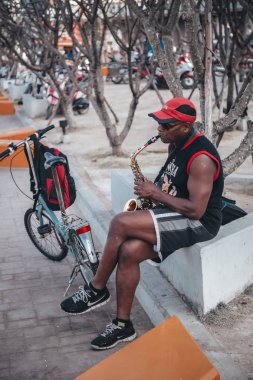 Bir adam parkta bisikletin yanında saksafon çalar Pattaya Tayland