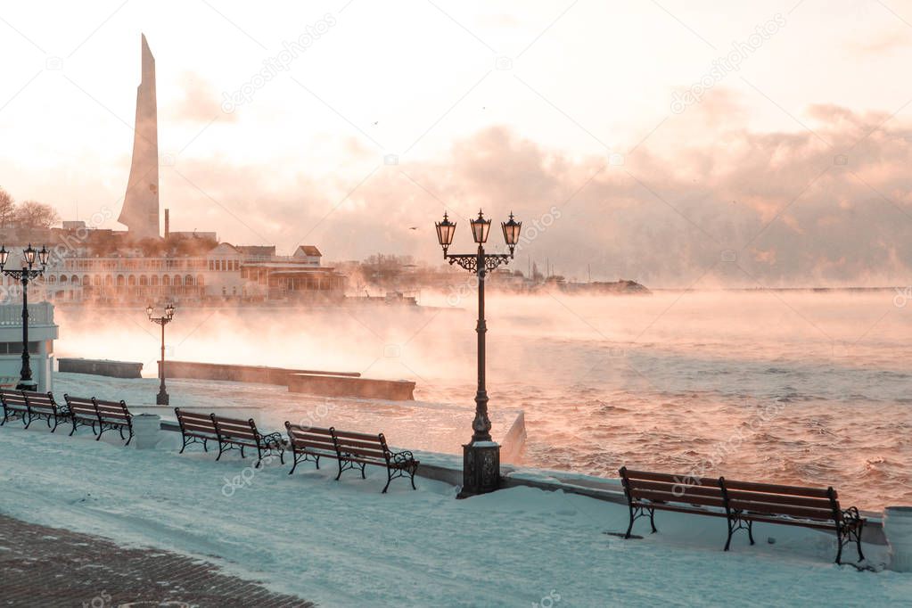 Empty embankment with wooden benches at foggy seaside in Sevastopol