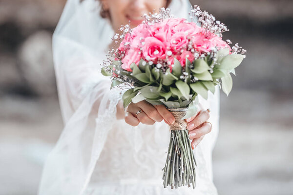 The bride holds a wedding bouquet from pink flowers