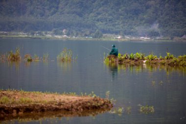 Ormanın ortasındaki gölde bir balıkçı.