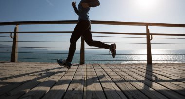 Sahil sahil üzerinde gündoğumu sırasında çalışan sportif kadın runner 