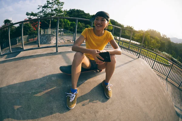 Vrouwelijke Skateboarder Zittend Het Skateboard Het Gebruik Van Mobiele Telefoon — Stockfoto