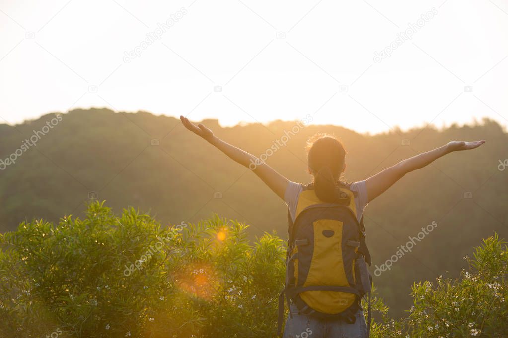 Cheering woman hiker enjoying the beautiful view on sunrise mountain top
