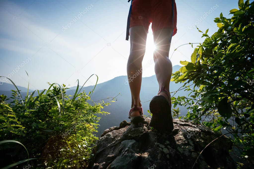 successful hiker legs on summer sunrise mountain top cliff edge