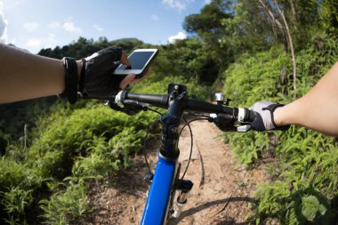 Tepenin üst üste binme, cep telefonu, holding rider Gps aramak için online başvuru kullanarak güneşli günde ormandaki bisiklet sürme sırasında koordinatları 