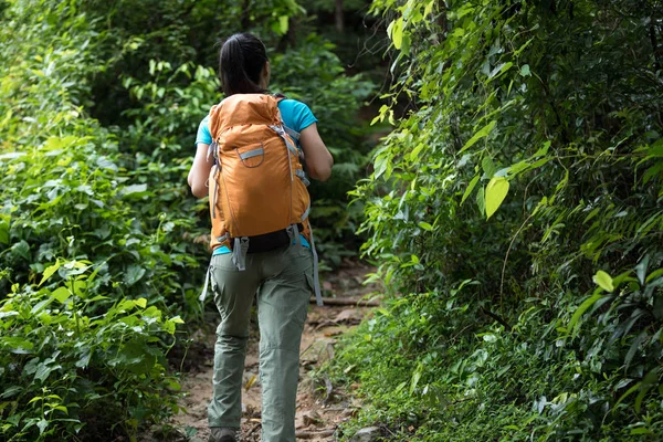 Woman hiking with backpack on forest trail