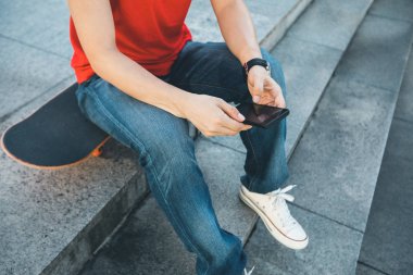 kaykay üzerinde oturan ve cep telefonuyla city adlı bir kaykaycı