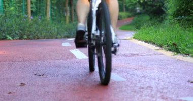 Kadın uzanmış silah ile güneşli park iz üzerinde bisiklete binmek