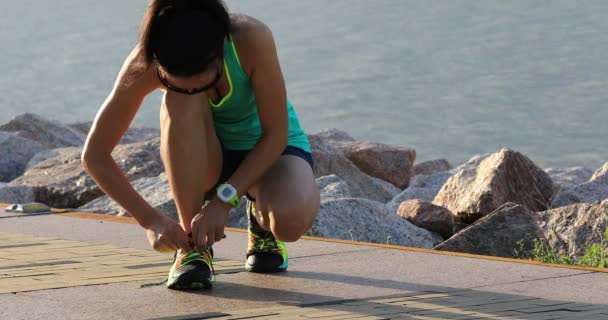 アスリート少女海辺にジョギングする前に靴ひもを結ぶ — ストック動画