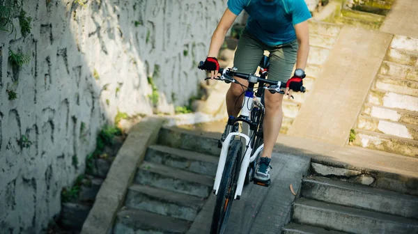 Woman biker riding down stairs in city