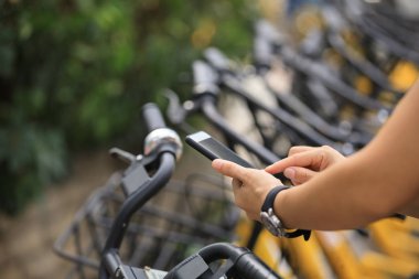 Akıllı telefon kullanan eller, şehirdeki paylaşılan motorun QR kodunu tarıyor