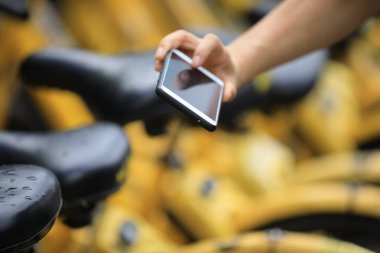 Akıllı telefon kullanan eller, şehirdeki paylaşılan motorun QR kodunu tarıyor
