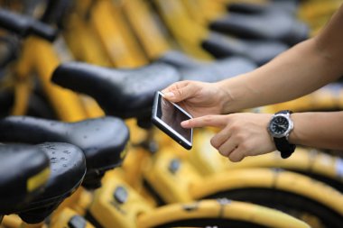 Akıllı telefon kullanan eller, şehirdeki paylaşılan motorun QR kodunu tarıyor