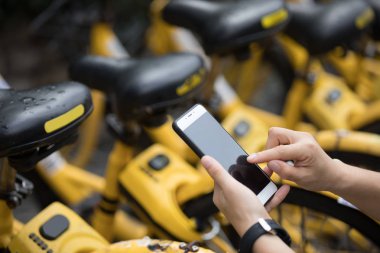 Akıllı telefon kullanan eller, şehirdeki paylaşılan motorun QR kodunu tarıyor