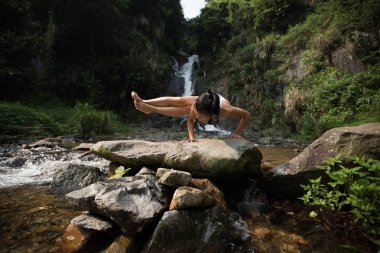 Genç kadın şelale orman içinde yakınındaki yoga yaparken