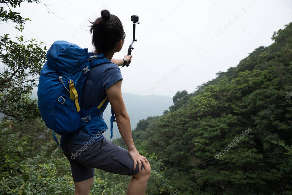 Woman Taking A Selfie with action camera while Hiking In Forest 