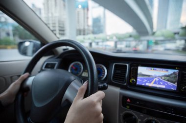 Şehir yolunda araba sürerken direksiyonu tutan eller 