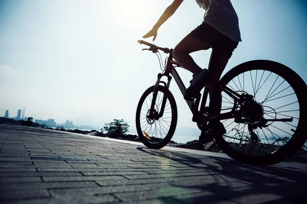 Hands free cycling woman riding Mountain Bike on sunrise seaside