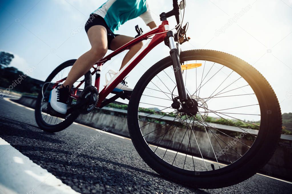 Woman cyclist riding Mountain Bike on highway