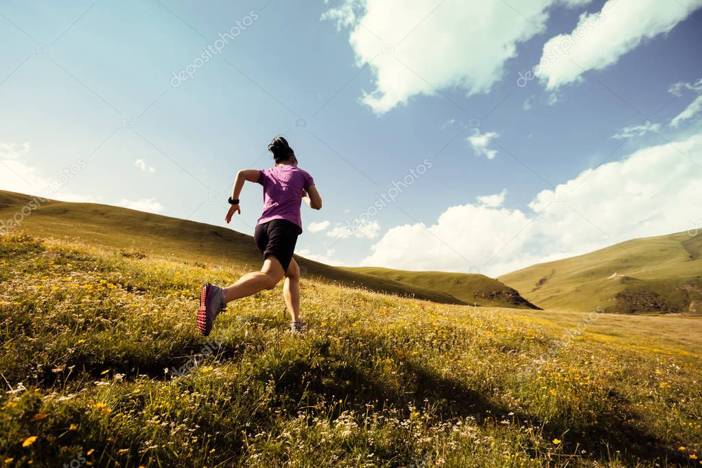 Young fitness woman trail runner running on grassland