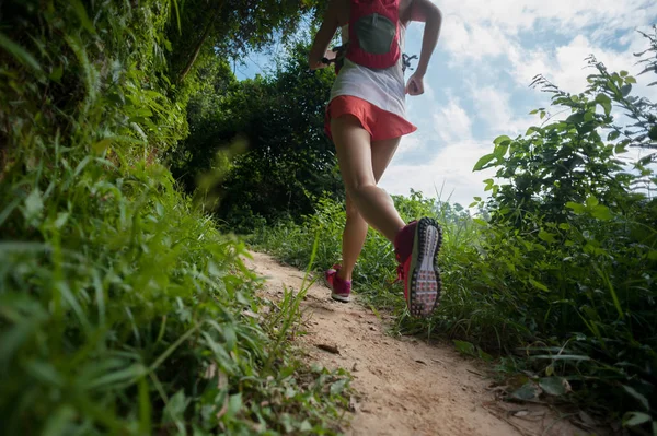 Young woman trail runner running on tropical forest trail