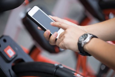 Akıllı telefon kullanan eller, şehirdeki paylaşılan motorun QR kodunu tarıyor