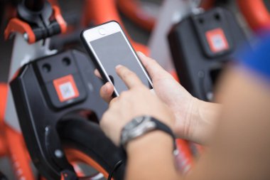 Akıllı telefon kullanan eller, şehirdeki paylaşılan motorun QR kodunu tarıyor