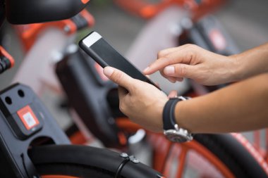 Akıllı telefon kullanan eller, şehirdeki paylaşılan motorun QR kodunu tarıyor