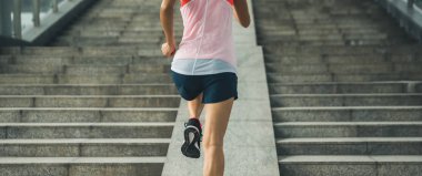 Koşu ve kentsel eğitim iş içinde çalışan bir şehir merdiven üzerinde çalışan genç kadın runner sporcumuz