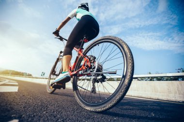 Genç kadın bisikletçi dağ bisiklet sürme karayolu üzerinde