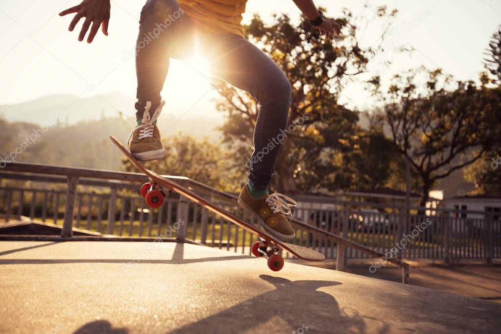 Skateboarder skateboarding at skatepark ramp at sunset