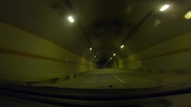Pohled na vozidlo čelním sklem auta pohybujícího se v tmavém tunelu 