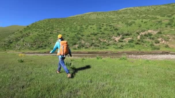 中国の山の緑の牧草地で若い女性のハイキング — ストック動画