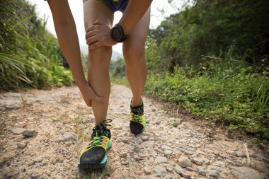 Asyalı kadın runner kayalık yolda yaralı spor bacağını tutun 